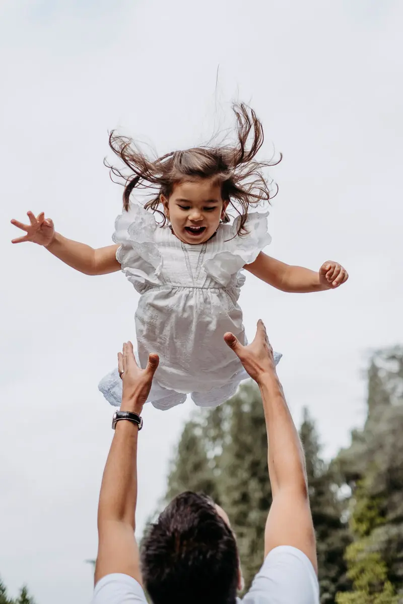 Mädchen fliegt in der Luft fröhliche Momente der Familienfotografie