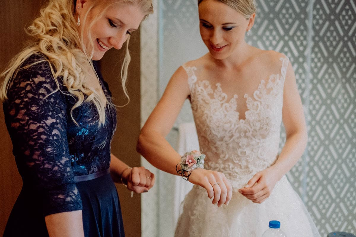 Braut beim Ankleiden, Hochzeitsfotografin hält emotionale Vorbereitungen für den Hochzeitstag fest.