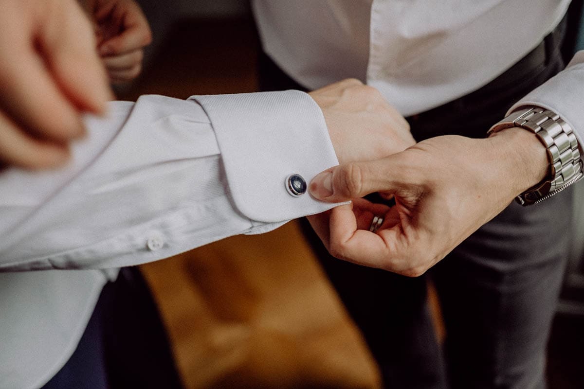 Bräutigam beim Ankleiden, Hochzeitsfotografin hält emotionale Vorbereitungen für den Hochzeitstag fest.